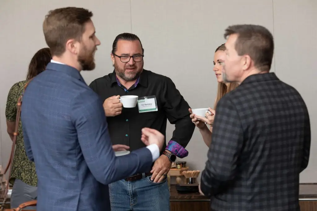 Business professionals holding coffee cups while networking during a conference break.