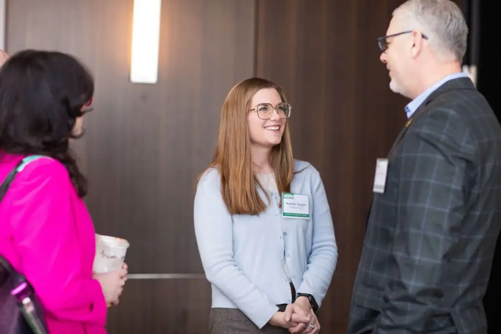 Three professionals talking and smiling during a networking session at a business conference.
